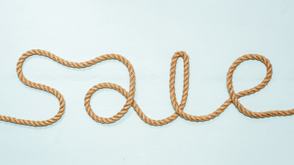 Inscription sale, made of rope, an invitation to the store for shopping at a discount. Isolated on a blue background.