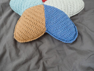 Closeup hand made multicolored yarn knitted pillow in the shape of a starfish on a gray background