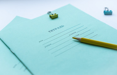 Two pupils copybooks with form to sign in: name, surname, grade, etc. with yellow pencil and paper clips on white background. Concept of education, minimalism. Selective focus.