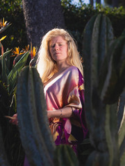 young woman with blond and albino hair dressed in a hand-painted silk clothes in nature relaxing