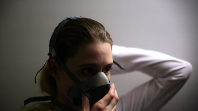Coronavirus Scientist/Doctor applies respirator and safety goggles, then looks into camera.