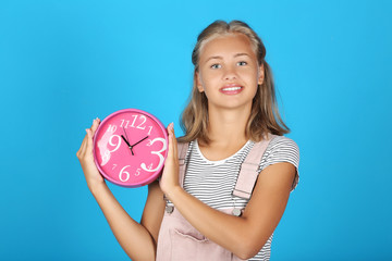 Young girl holding round clock on blue background