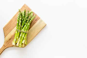 Cooking asparagus. Bunch steams on cutting board on white background top-down copy space