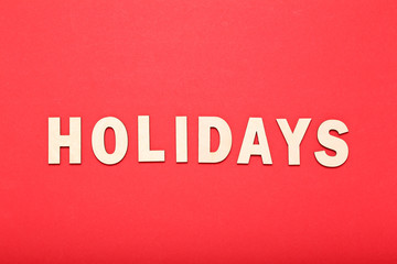 Word Holidays by wooden letters on red background