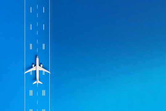 The passenger plane on airport runway and blue background with empty space for text. Top view, copy space