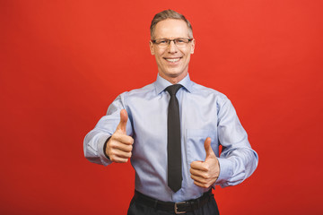 Well done! Close up portrait of delightful confident cool glad pleased cheerful excited aged senior business man demonstrating thumb up smile isolated on red background.