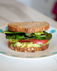 Homemade vegan sandwich with avocado, tomato, greens and vegan bacon