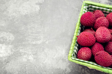 Tasty lychee in basket on grey background