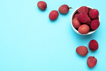Tasty lychee in bowl on blue background