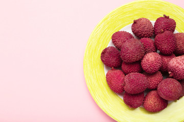 Tasty lychee in plate on pink background