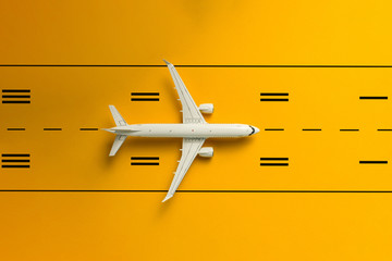 The passenger plane on airport runway and yellow background. Top view, Travel and adventure concept