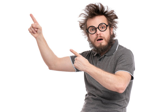 Crazy Scared Or Shocked Bearded Man With Funny Haircut In Eyeglasses Looks Worried. Silly, Afraid Or Surprised Guy Pointing Finger At Copy-space Or Something, Isolated On White Background.