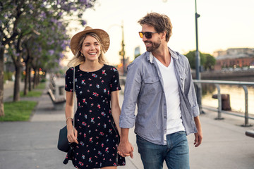 Smiling young couple walking on street during sunset