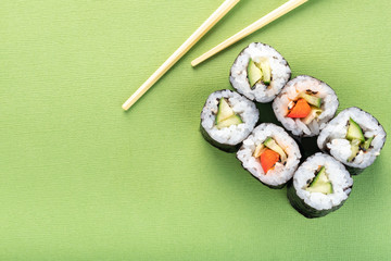 Vegetarian sushi roll set with vegetable filling and chopsticks on a green background