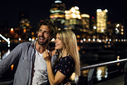 Smiling young couple looking away while standing outdoors at night