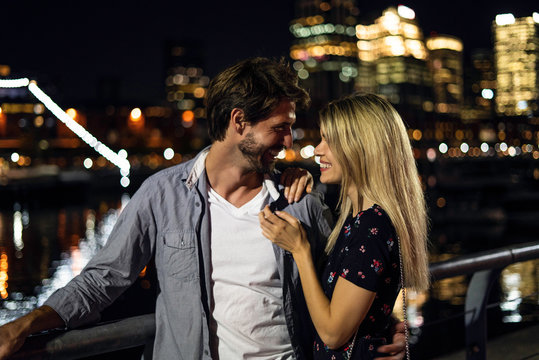 Smiling young couple looking at each other while standing outdoors at night