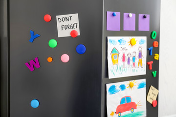 Modern refrigerator with child's drawings, notes and magnets, closeup