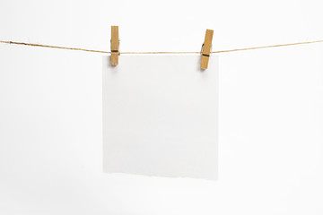 Single torned paper sheet for notes that hang on a rope with clothespins and isolated on white....