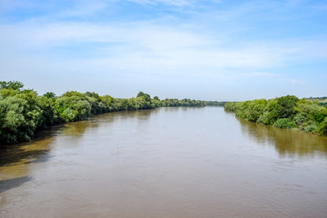 Passing over the bridge over river. The landscape of the river, the surface and the trees of the river's waterplain.