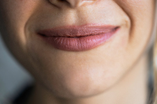 Close-up of smiling young woman lips with pink lipstick