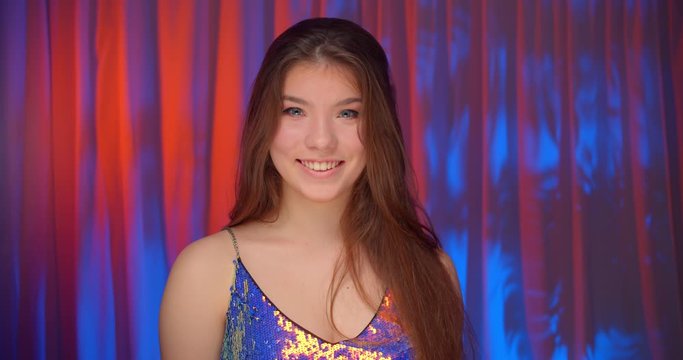 Portrait caucasian beautiful confident girl neon light look at camera bare shoulders sparkle shine background