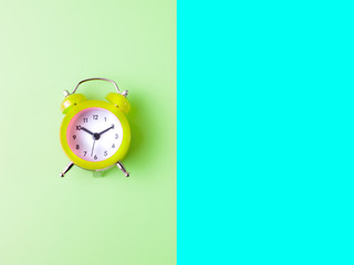 green alarm clock isolated on green and blue background