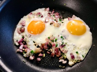 Sunny Side Up Frying Eggs in Pan with Red Onions and Chives for Breakfast in Plate. Organic Food.