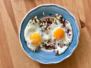 Sunny Side Up Fried Eggs with Red Onions and Chives for Breakfast in Plate. Organic Food