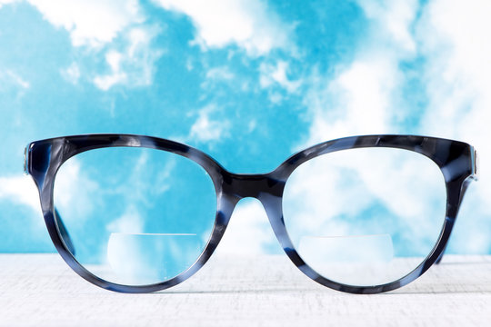 Eyeglasses Glasses with Bifocals and Black Blue Frame smudged agaist a blue and cloudy sky