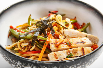 Wok udon with vegetables and chicken closeup view