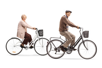 Fototapeta premium Senior man and senior woman riding bicycles and smiling at the camera