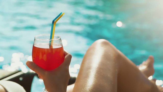 Woman with cocktail relaxing near the swimming pool.