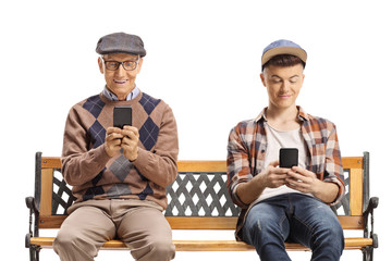Senior man and a young guy sitting on a bench and using mobile phones