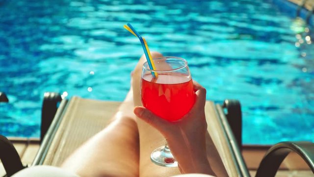 Woman with cocktail relaxing near the swimming pool.