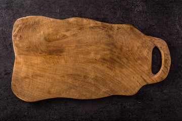 Empty wooden cutting board on black background top view