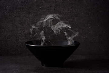 Black bowl with smoke on black background