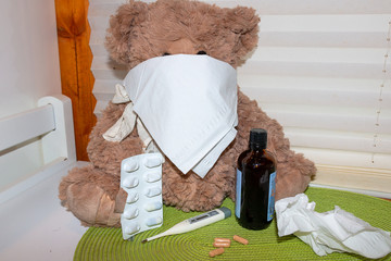 Teddy bear with face mask, clinical thermometer and medication for colds, influenza and corona virus