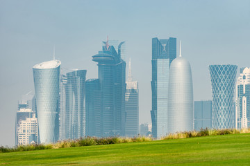 Fototapeta na wymiar Panoramic view of modern skyline of Doha with green grass foreground. Concept of healthy environment