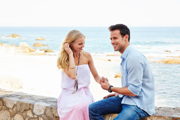 Young couple sitting along the ocean at a resort