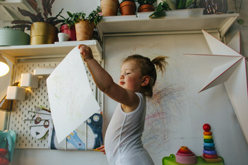 Girl holding her painting at home