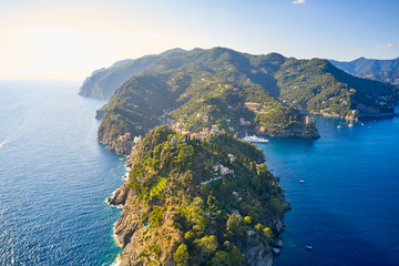 Arial view on the mountain range with a white lighthouse near Ligurian sea on the foreground. Tradition colorful italian houses are loceted on the top of the hill.