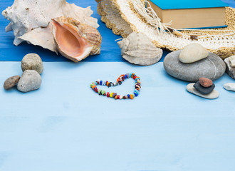 Obraz na płótnie Canvas Summer sea vacation. Travel and vacation items on blue wooden table. Beach accessories: Sea shells, sea pebbles, panama hat. Top view with copy space