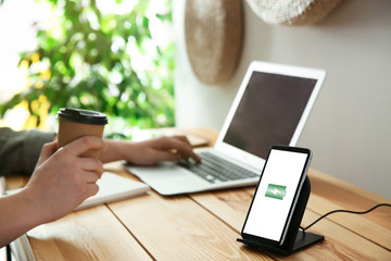 Man working at table while his mobile phone charging with wireless device