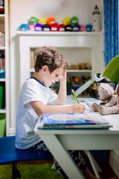 Small boy doing homework at desk in his bedroom