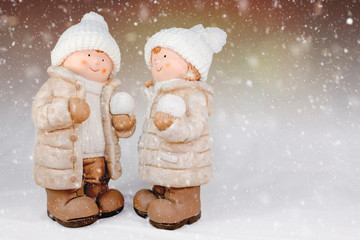Figuren eines Mädchen und Jungen mit weißer Wollmütze und Schneeball in der Hand vor...