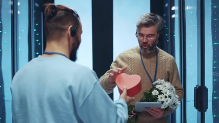 IT specialist gifting a heart-shaped box and flowers to his male colleague valentine at server room. Offended and amazed man rejecting a present fighting back with flowers kicking out. Lgbt. Everyone - Powered by Adobe