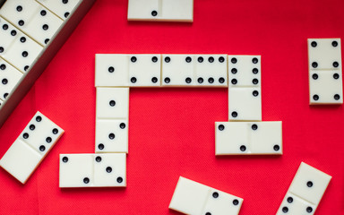 Dominoes White dominoes lie during the game on a red fabric background and there is a lot of space for text. Play dominoes