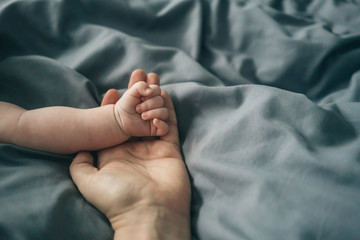 Close up of baby's hand resting on his mother's hand