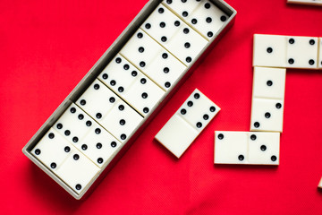 Dominoes Old domino bones lie in a gray case and near it on a red fabric background and a lot of space for text