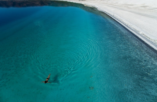 Woman swimming in turquoise lake
